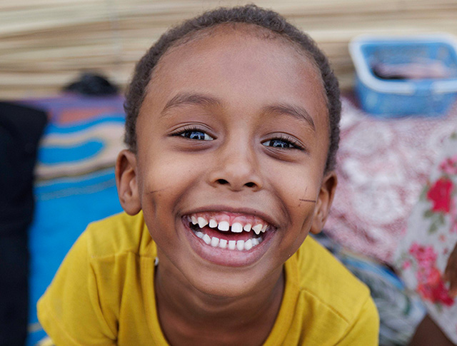 Eloge helps her brother put his face mask on